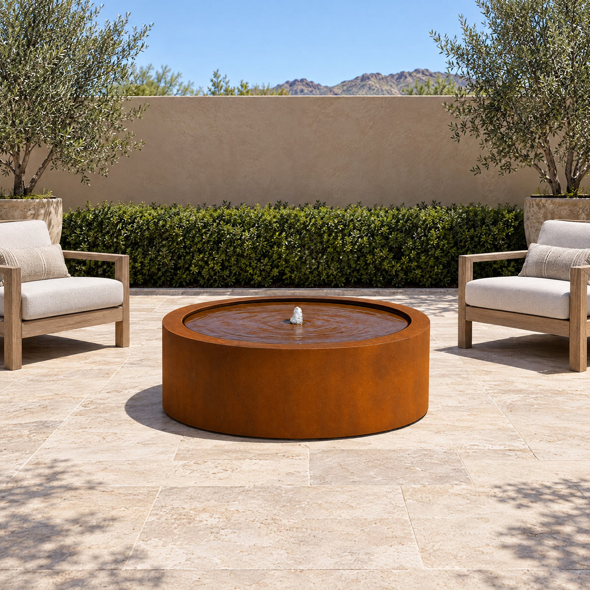 Corten steel Mesa Circular fountain centered on a stone terrace between two lounge chairs