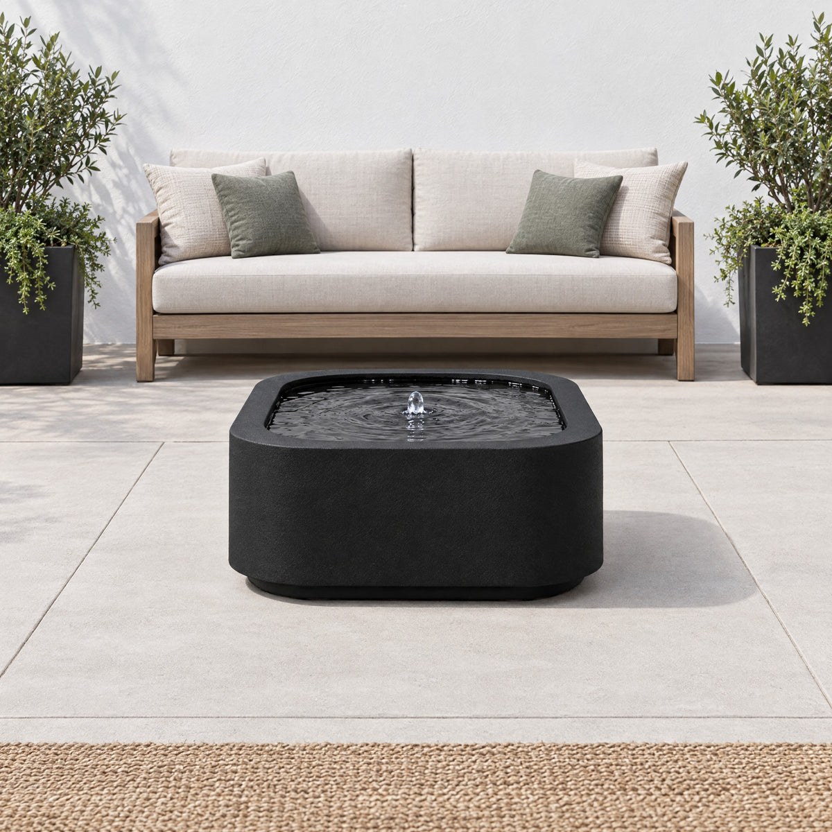 Black steel Mesa Soft Square fountain on a modern terrace in front of an outdoor sofa