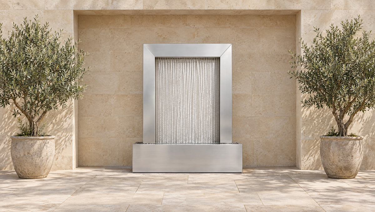 Stainless steel rain curtain fountain in a limestone wall niche between two potted olive trees